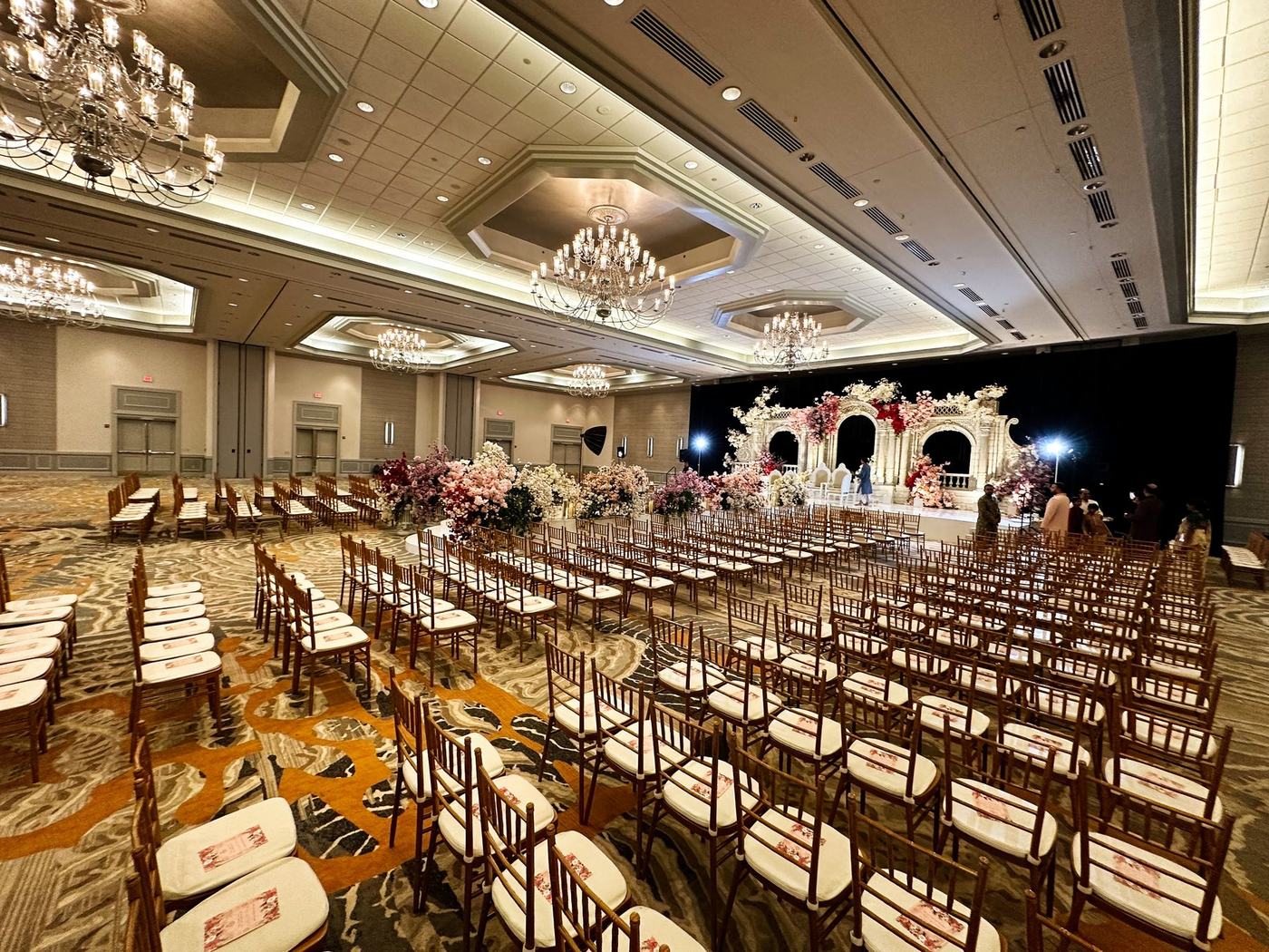 Hotel ballroom set for the ceremony with chandeliers and rows of gold chairs