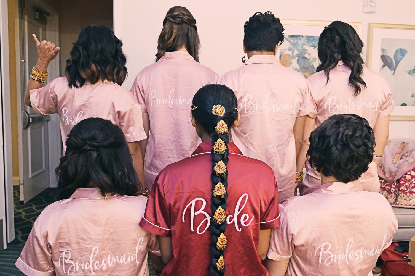 Bride and bridesmaids in monogrammed robes, seen from behind