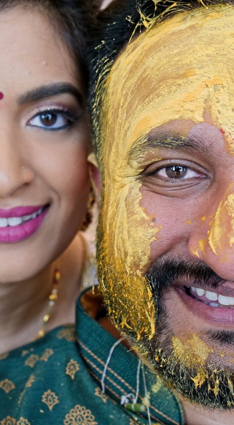 Bride and groom, half their faces in haldi