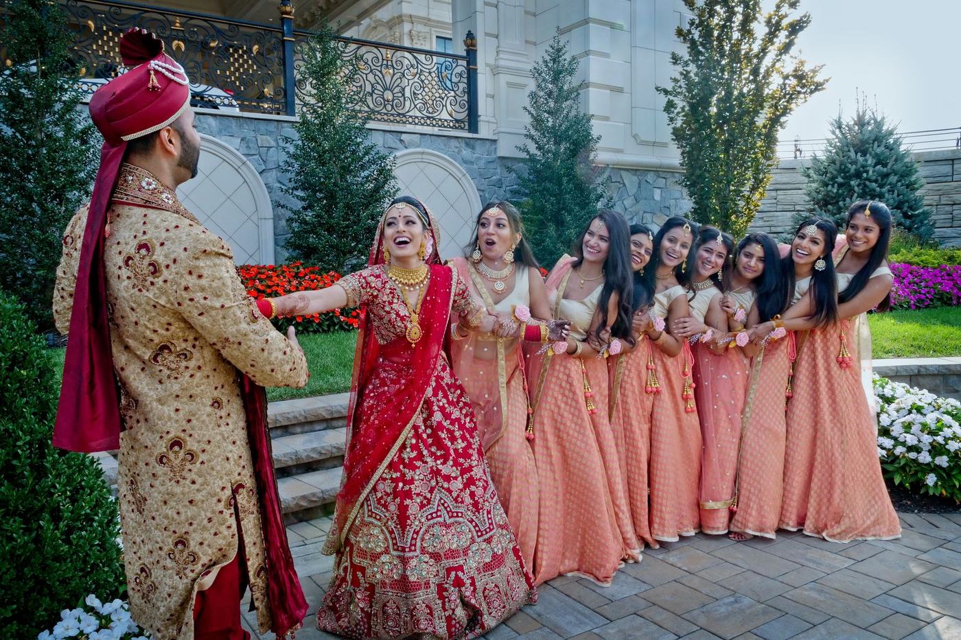 Bride and groom with the bridesmaids in peach outside the estate