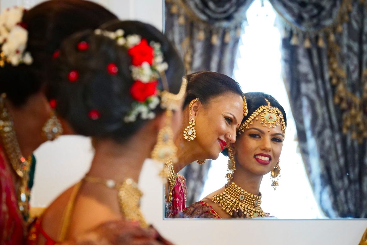 Bride and her mother sharing a look in the mirror as she gets ready