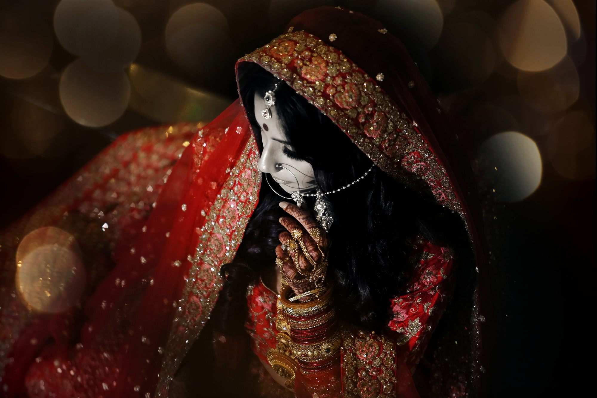 A bride in a quiet moment beneath her red dupatta