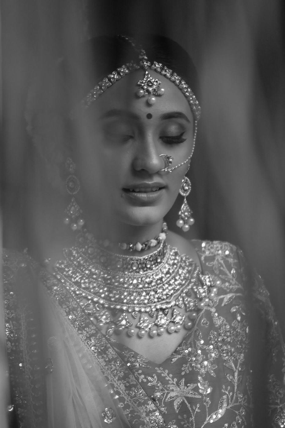 Bride with eyes closed beneath her veil, in black and white