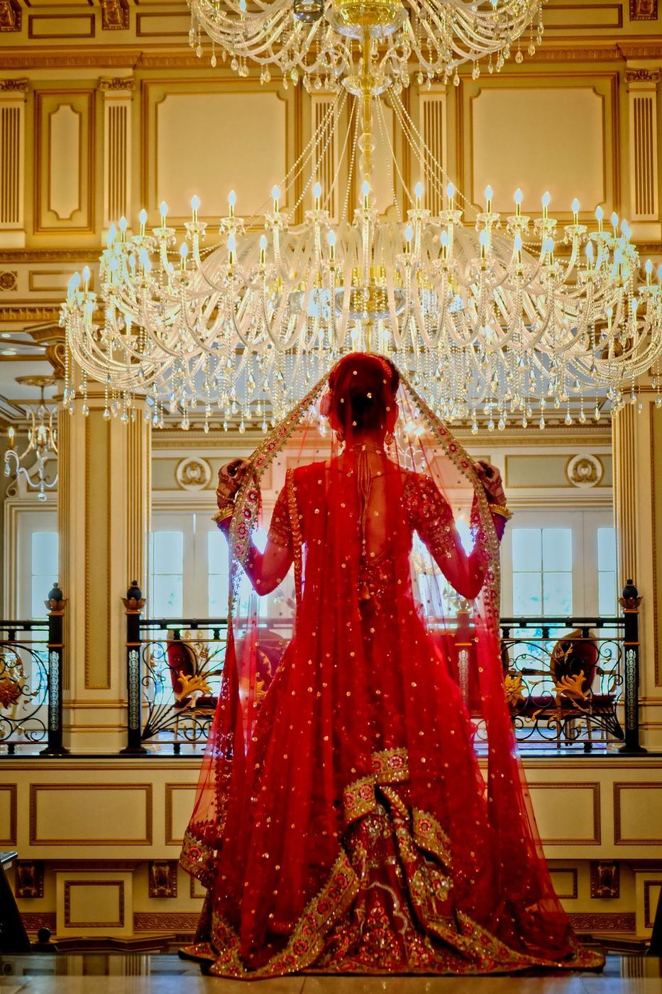 Bride from behind beneath the chandelier of The Legacy Castle