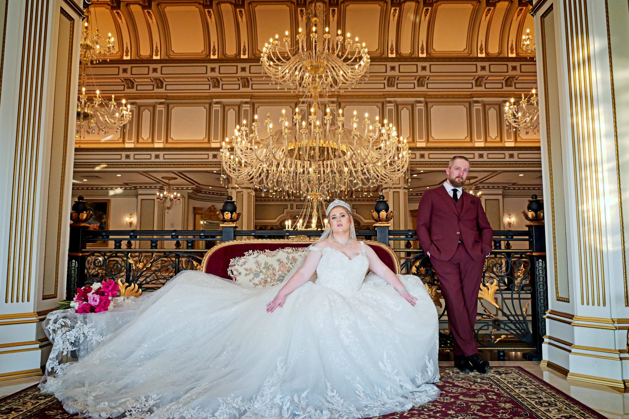 Bride and groom together beneath the chandeliers of a grand ballroom