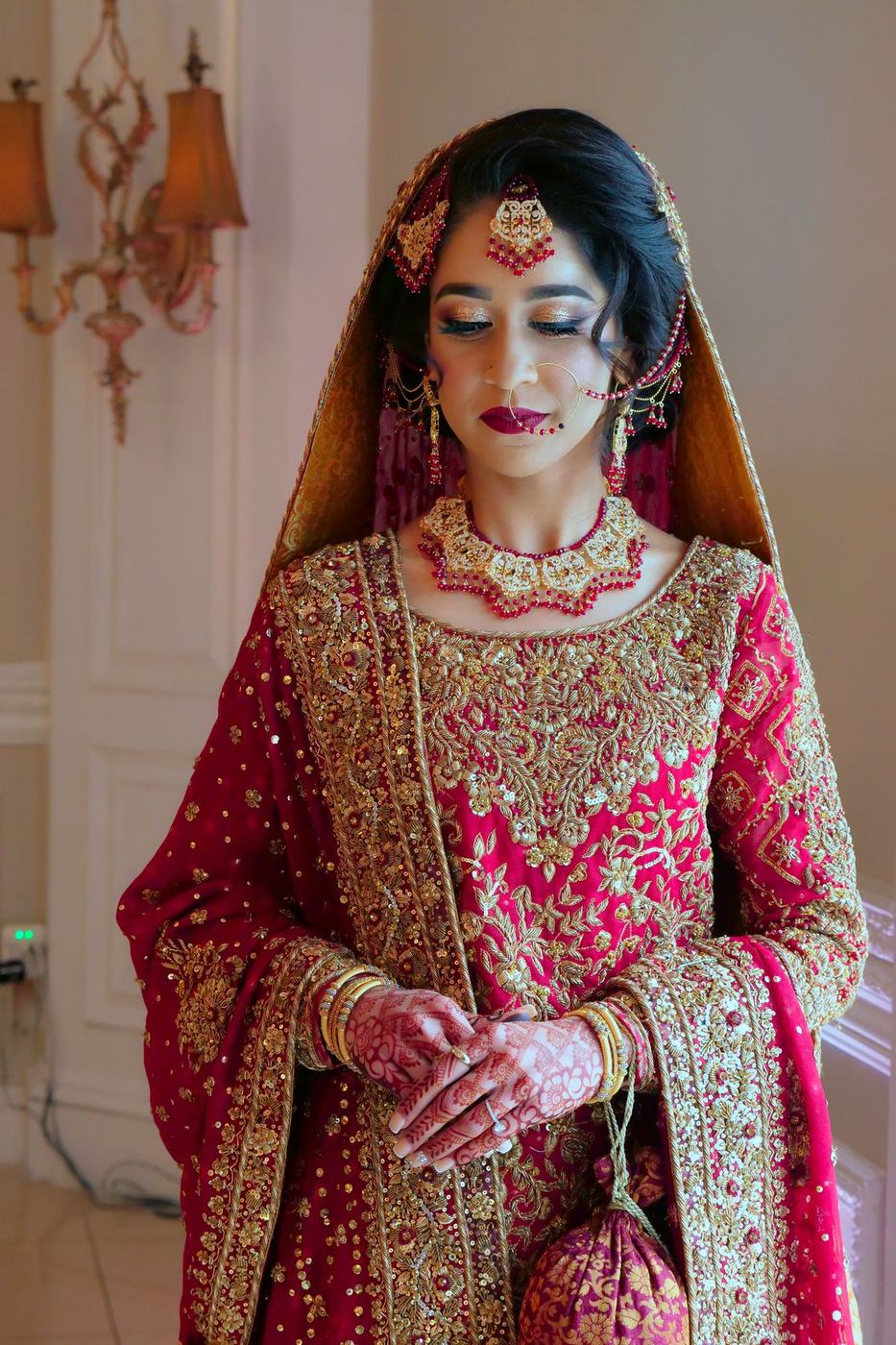 Bride in a magenta and gold gharara, eyes lowered