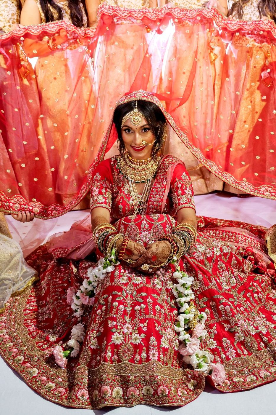 Bride in red and gold seated beneath her veil
