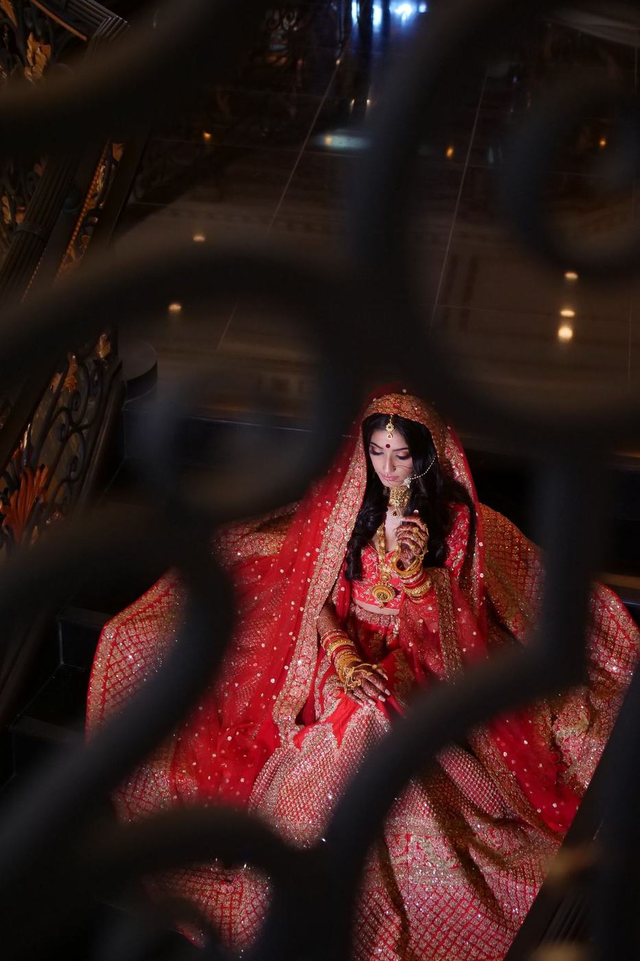 Bride in red glimpsed through an iron lattice