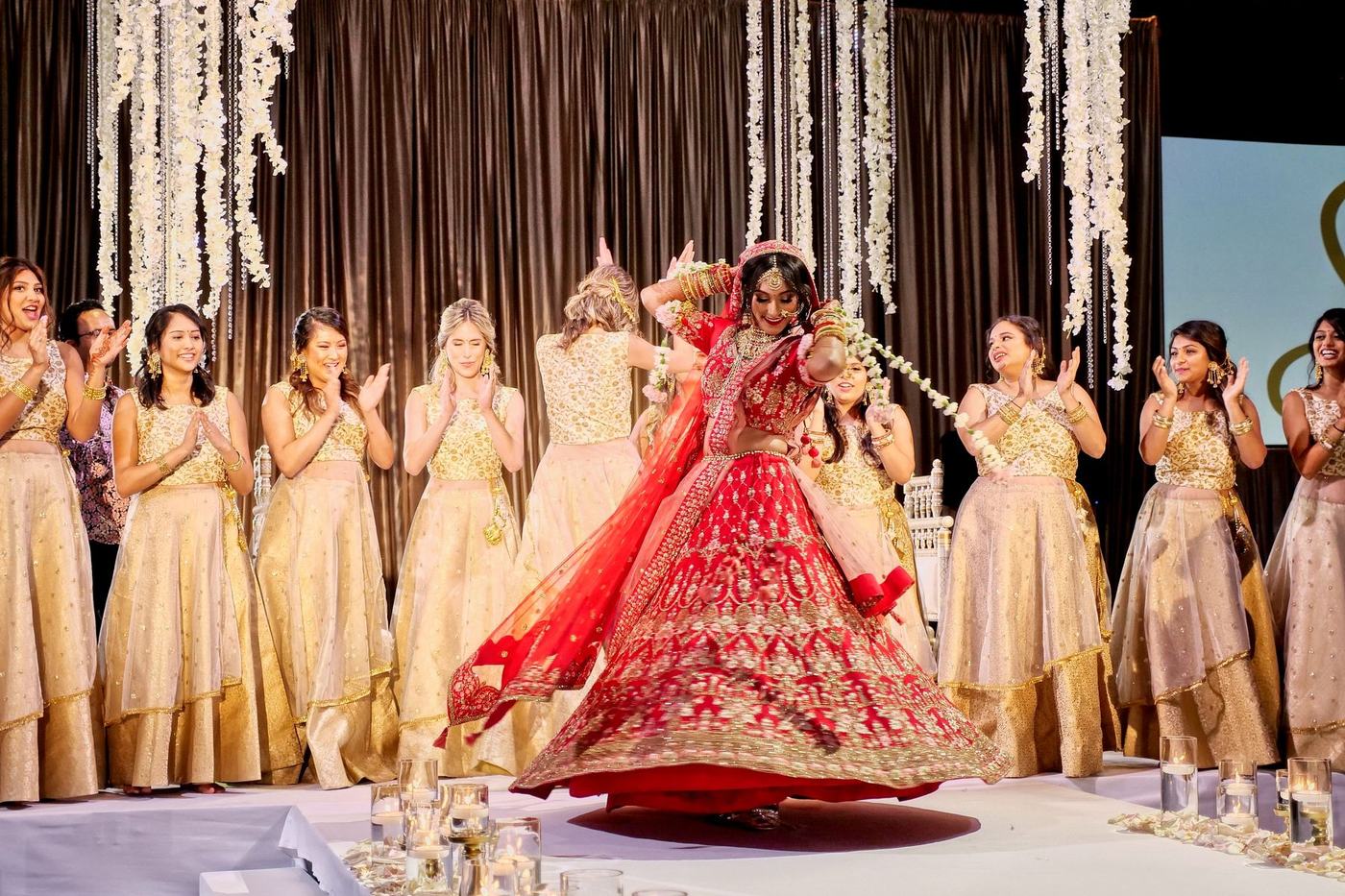 Bride in red with her bridesmaids in gold cheering on the stage