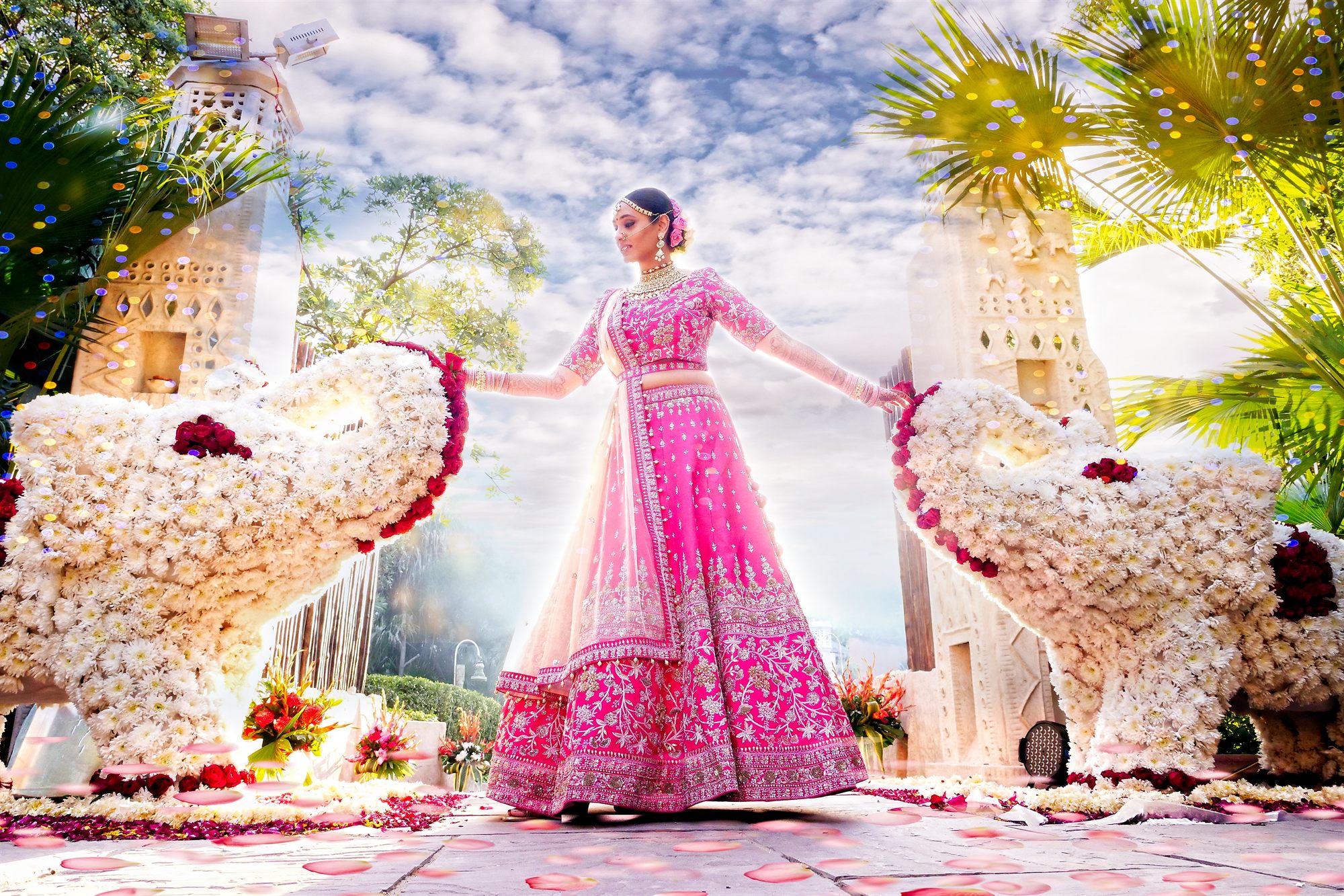 Bride in a pink lehenga before a floral mandap in the open air