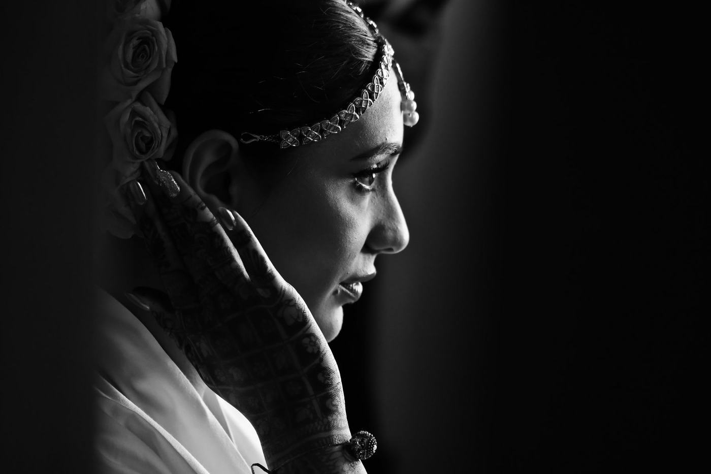 Bride in profile with a hand to her cheek, in black and white