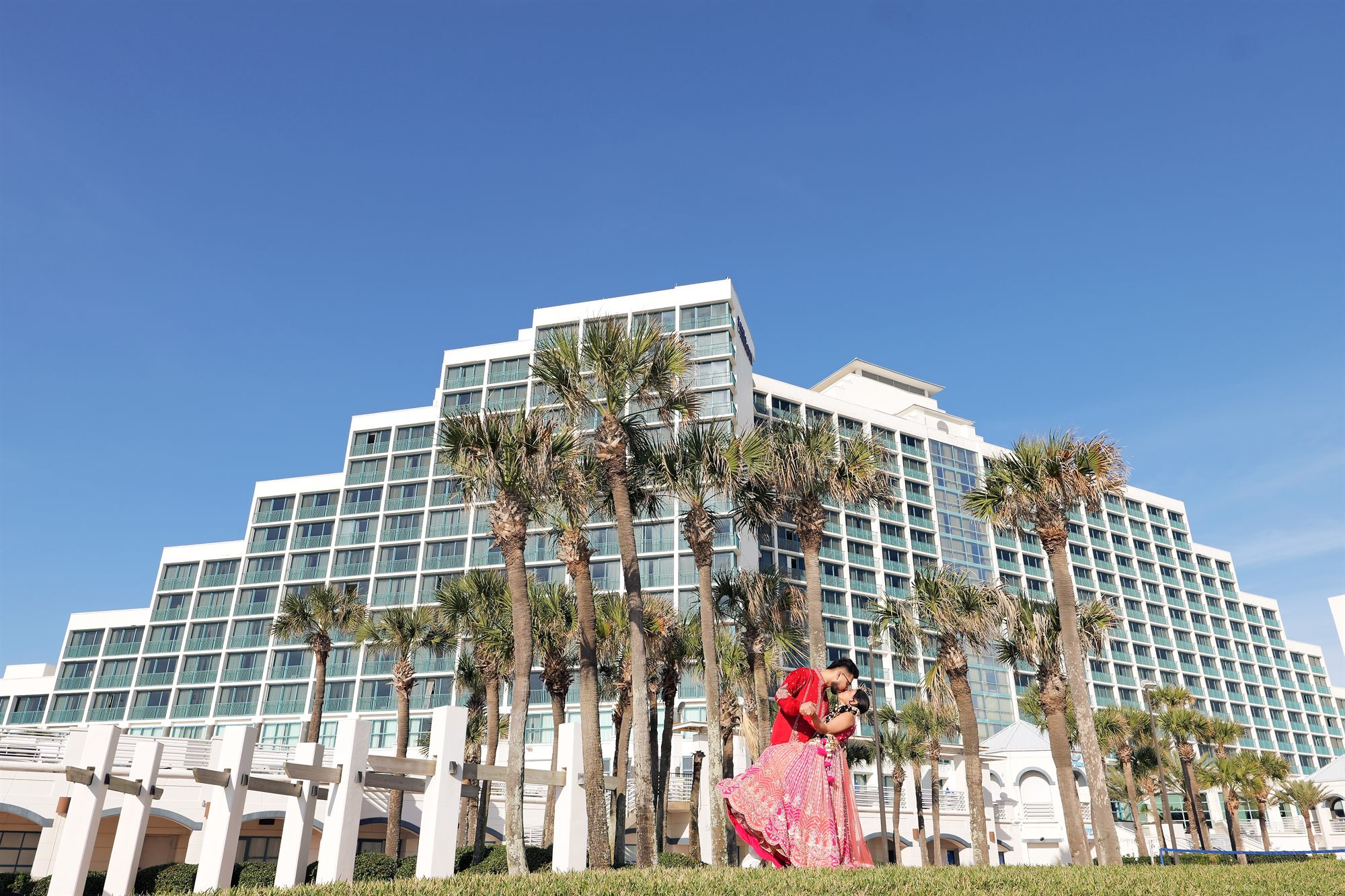 Bride crossing the lawn in front of a wide resort facade
