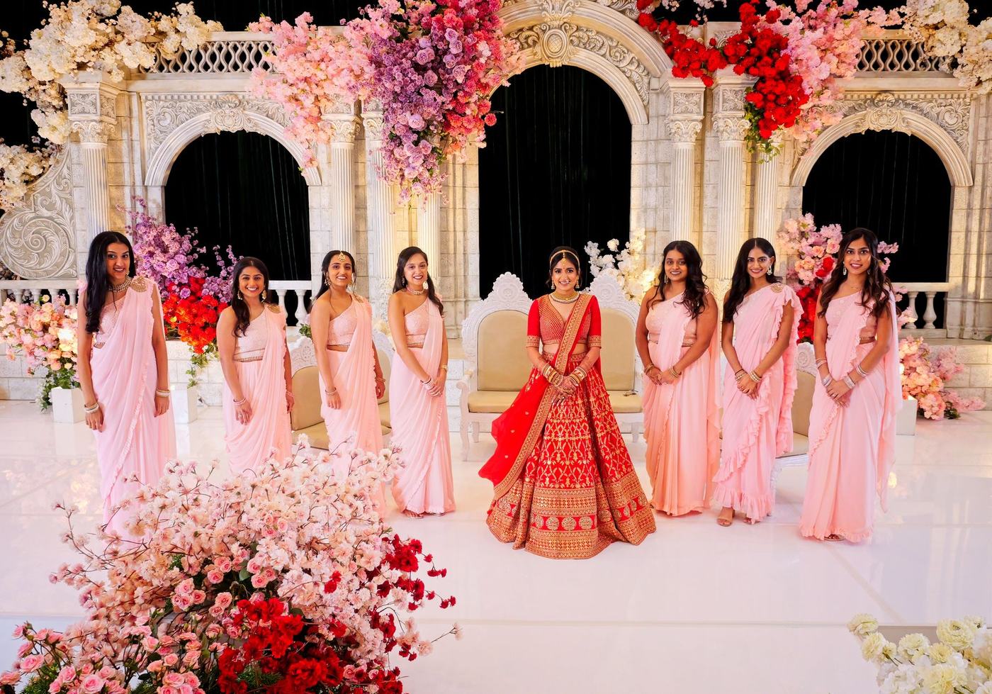 Bride in red with her bridesmaids in pink on the reception stage