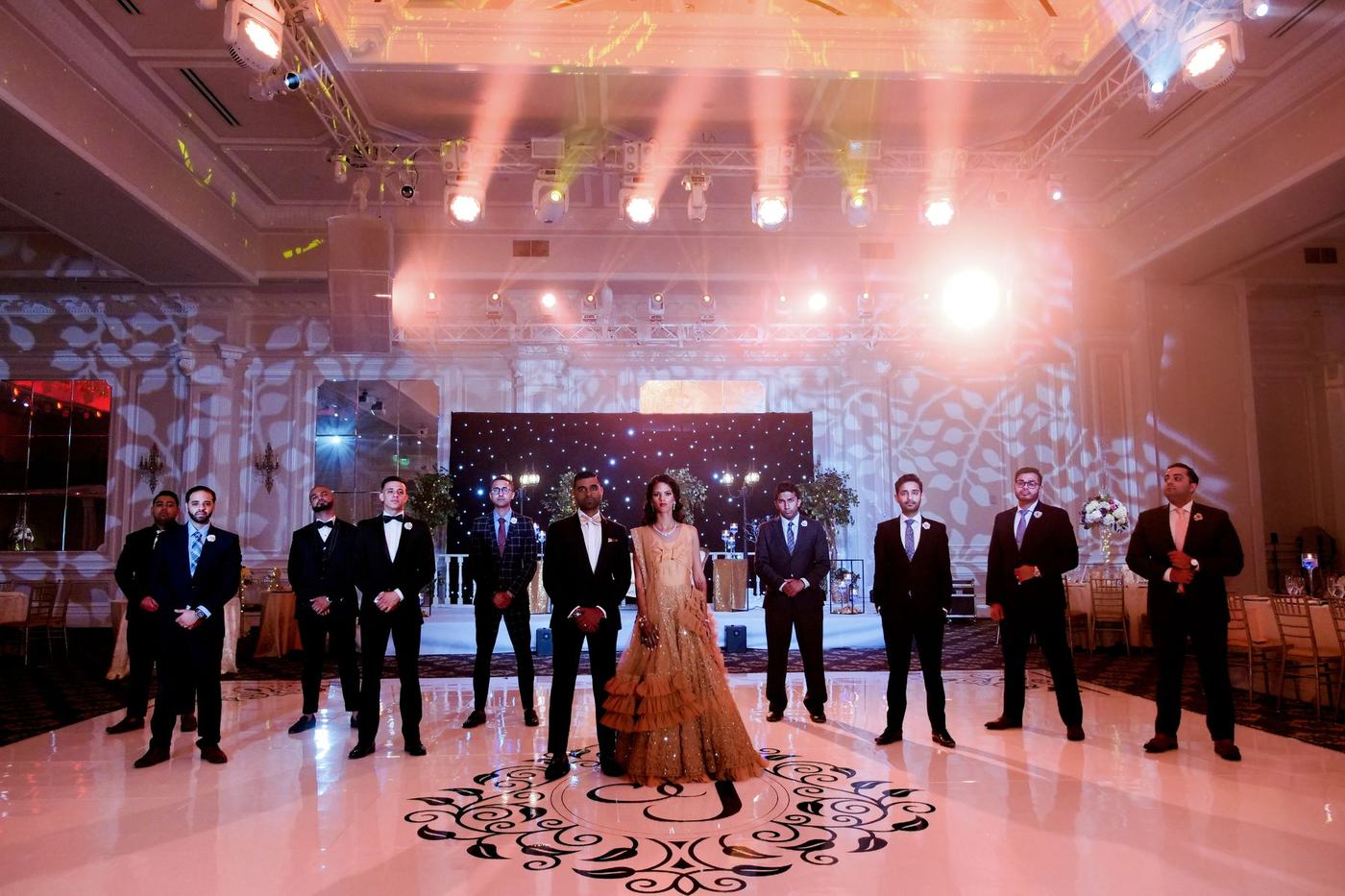 Bride in gold with the groomsmen in black on the reception floor