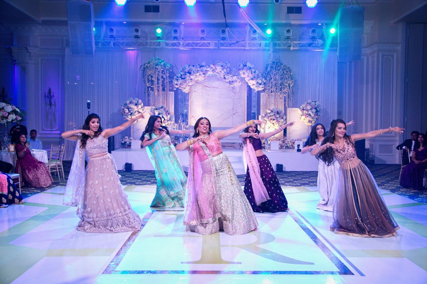 Bridesmaids dancing on the reception stage in pastels