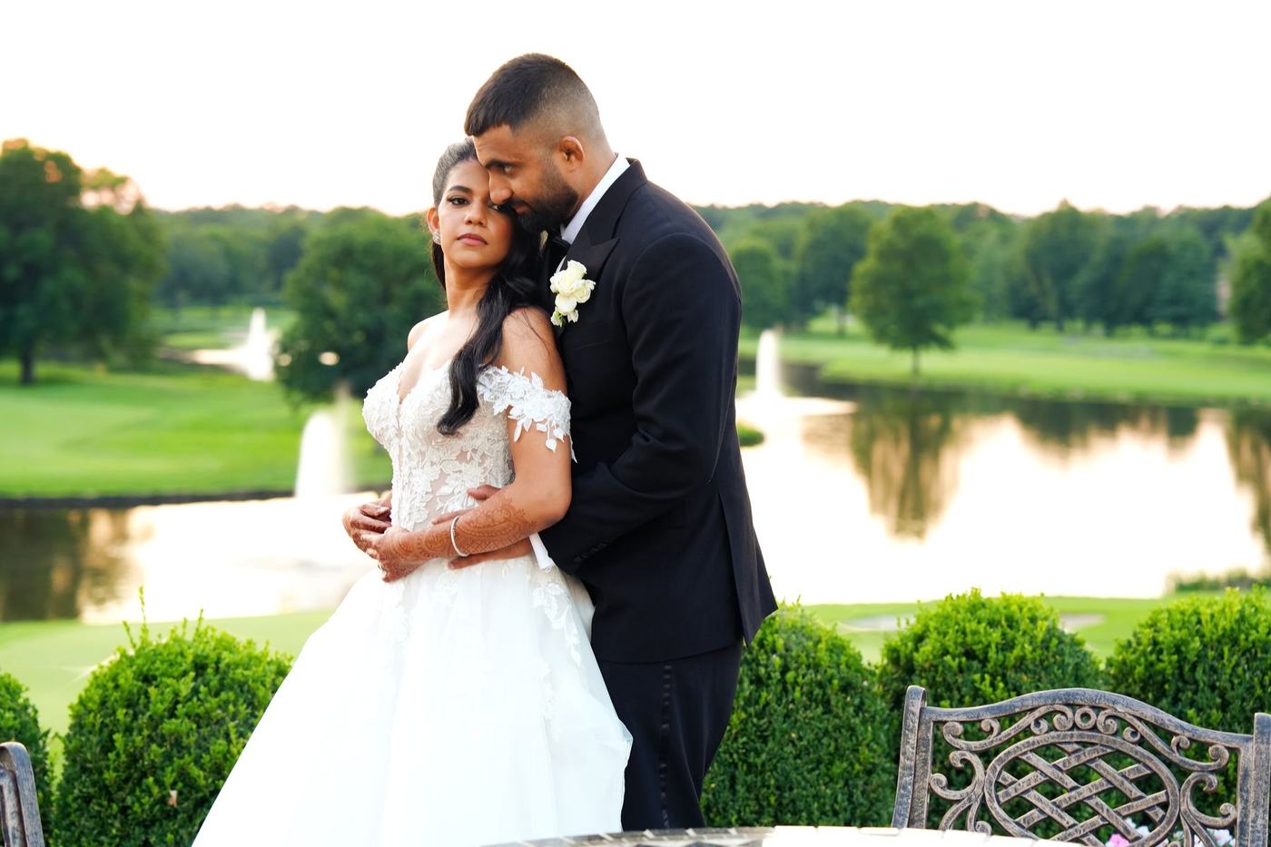 Bride in a white gown and groom in a tuxedo by the lake at Brooklake Country Club