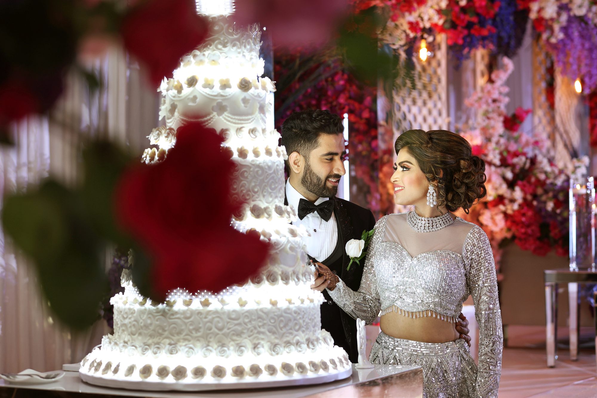 Couple laughing together, framed through the tiers of their wedding cake