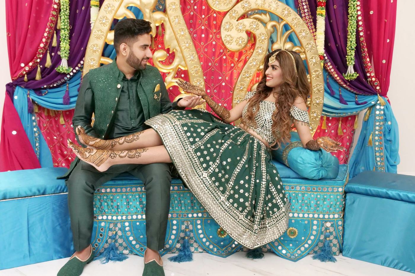 Couple in green on the turquoise sofa of their sangeet stage