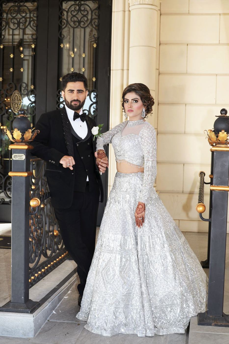 Couple in silver and black tie at ornate iron gates