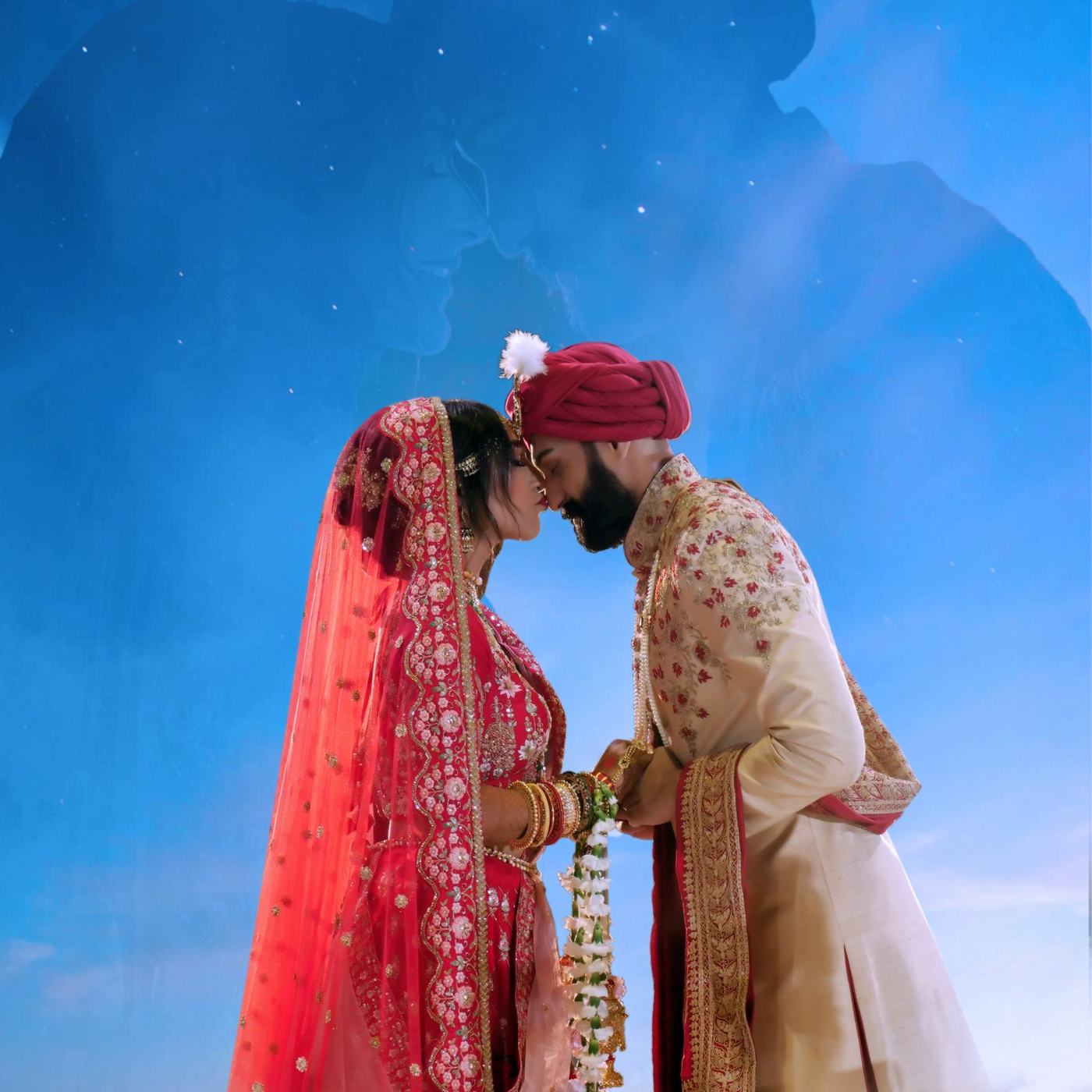 Couple in red and ivory kissing under a bright blue sky