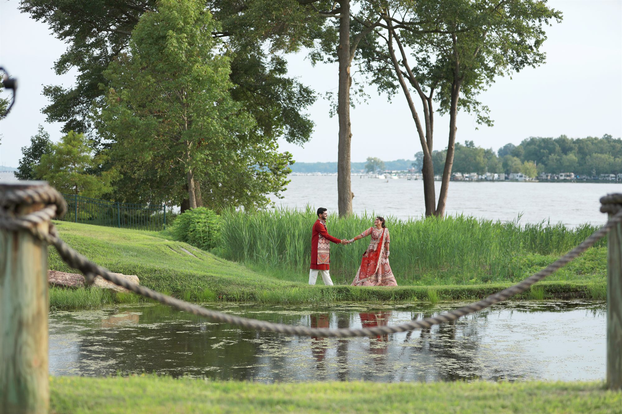 Couple walking together along a quiet lakeshore beneath old trees
