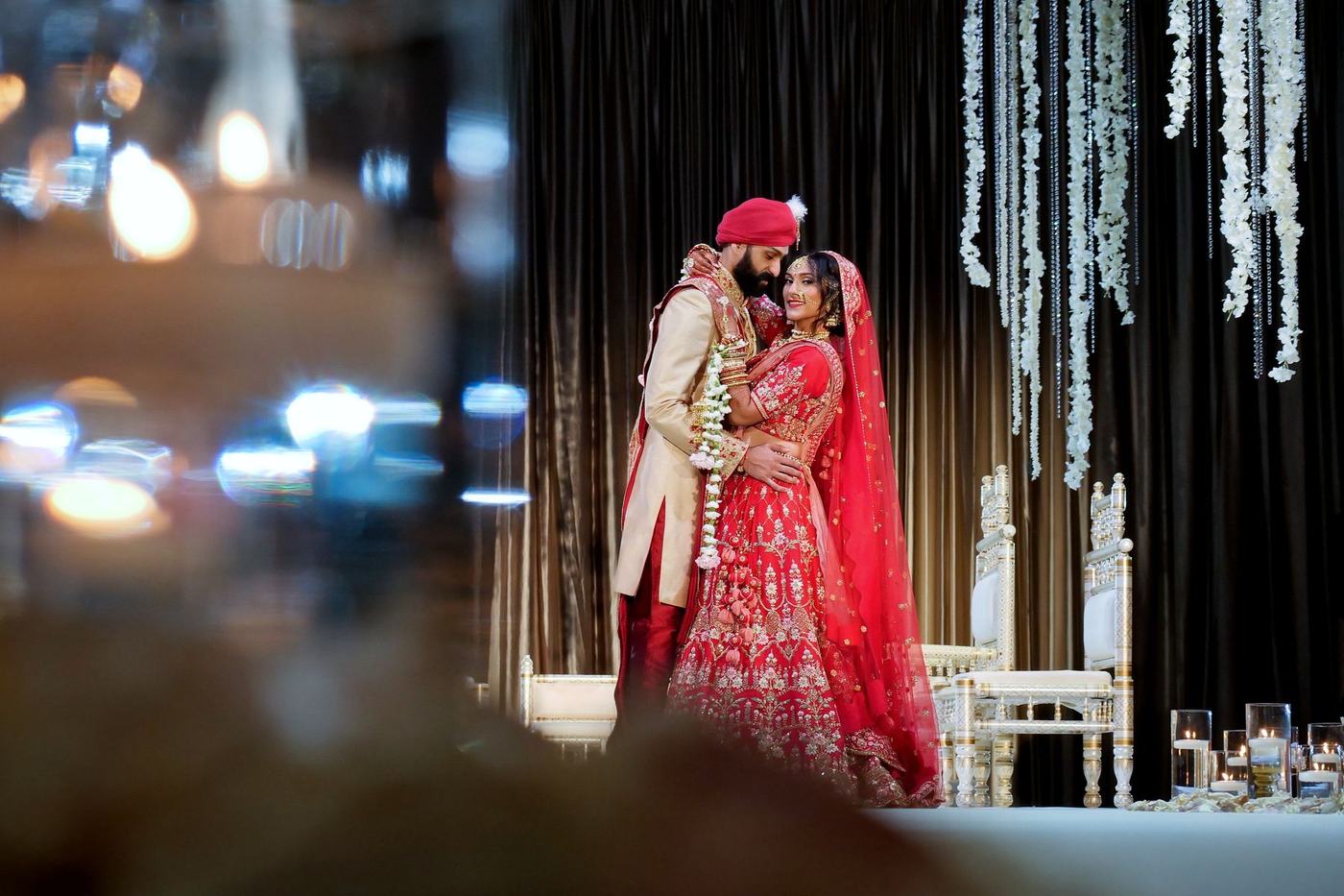Couple on the reception stage seen through candle bokeh