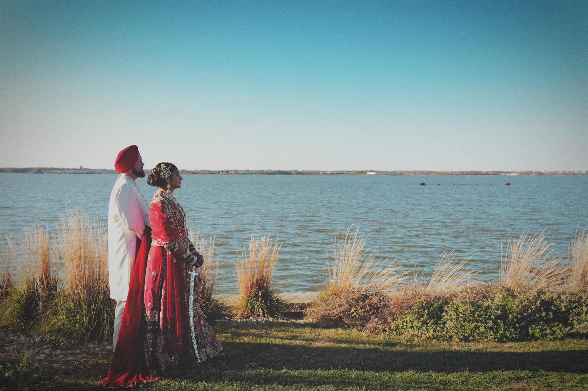 Couple standing side by side against a wide open bay at dusk