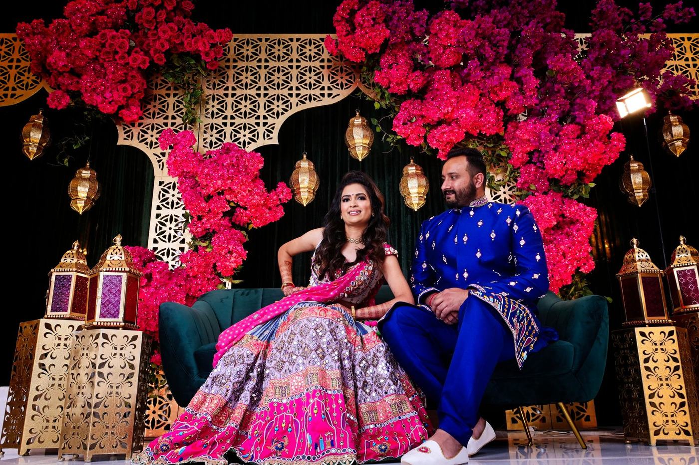 Couple seated on the sangeet stage in pink and blue