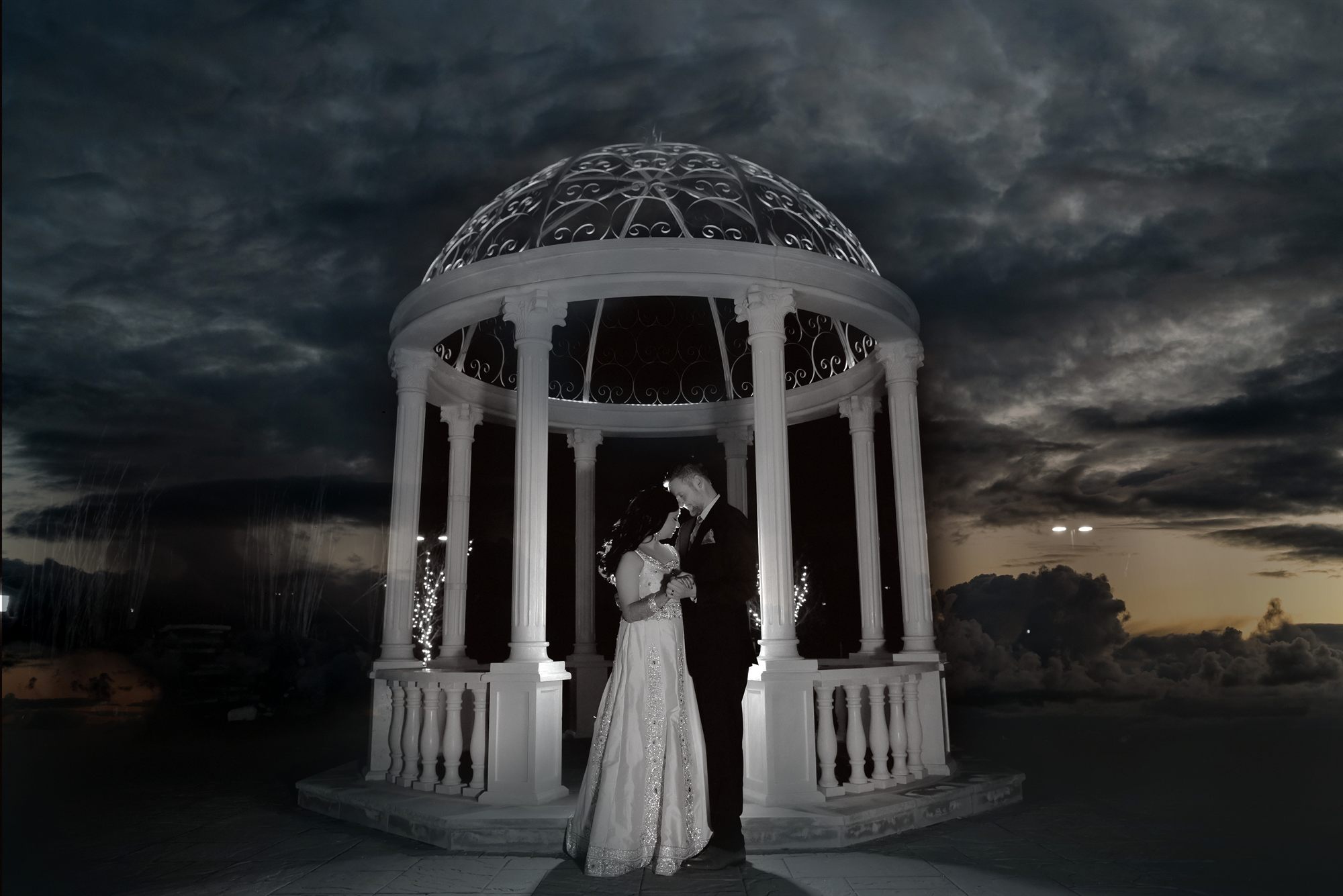 Couple beneath a white gazebo under a dark and dramatic sky