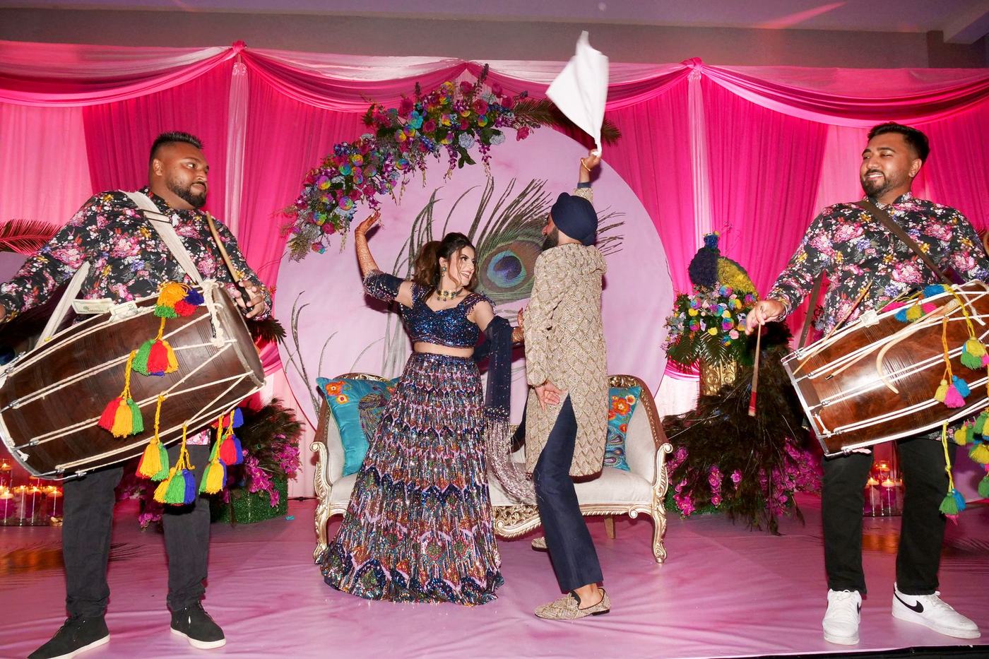Dhol players flanking the couple on the pink sangeet stage
