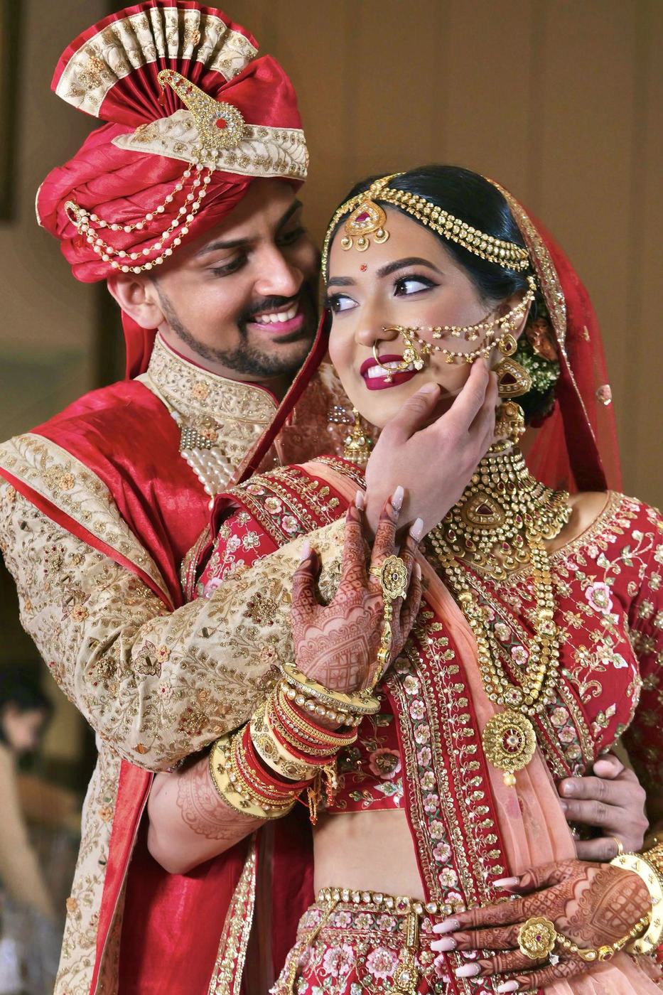 Groom in a red safa cupping the bride's face