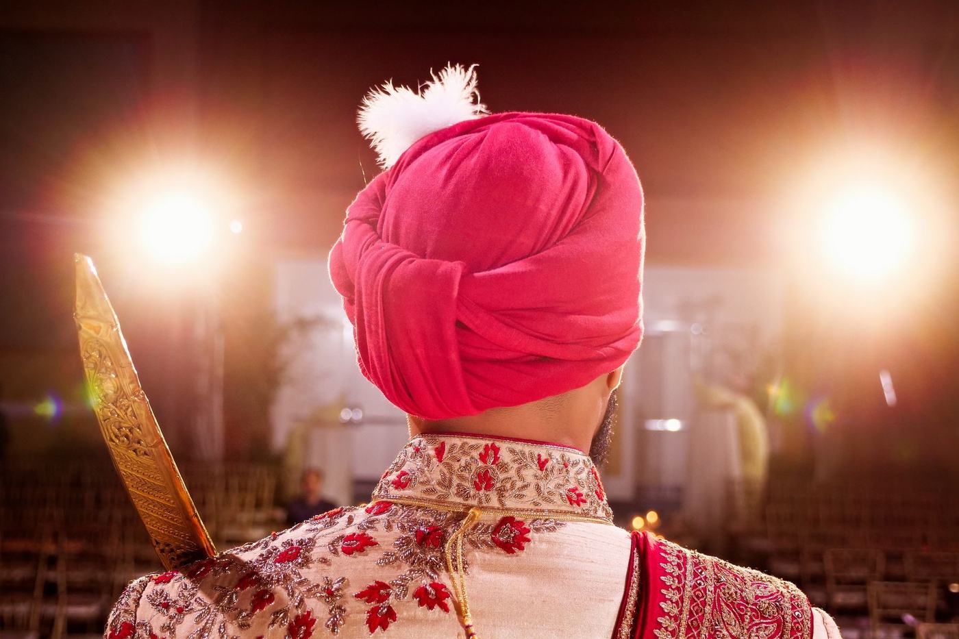 Groom from behind in a pink safa under the stage lights