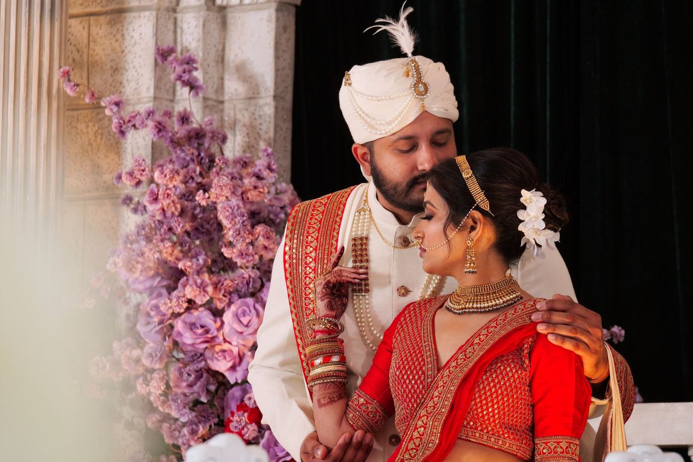 Groom kissing the bride's forehead among lilac florals