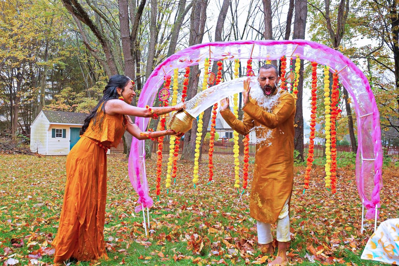 Haldi beneath marigold strings on a lawn of autumn leaves