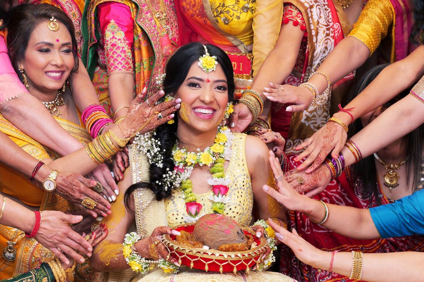 Family hands reaching in to bless the bride at her haldi
