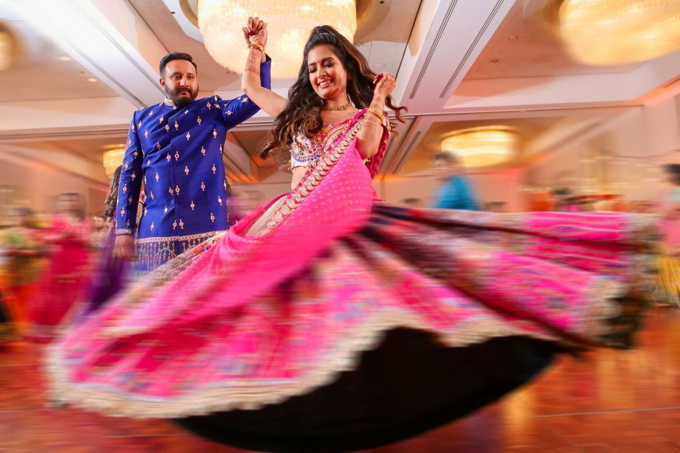 The bride's pink lehenga blurring as she spins