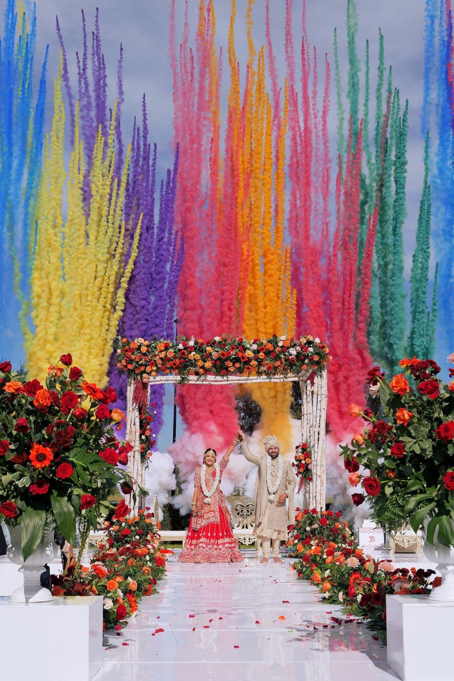 Outdoor mandap in a burst of rainbow coloured smoke