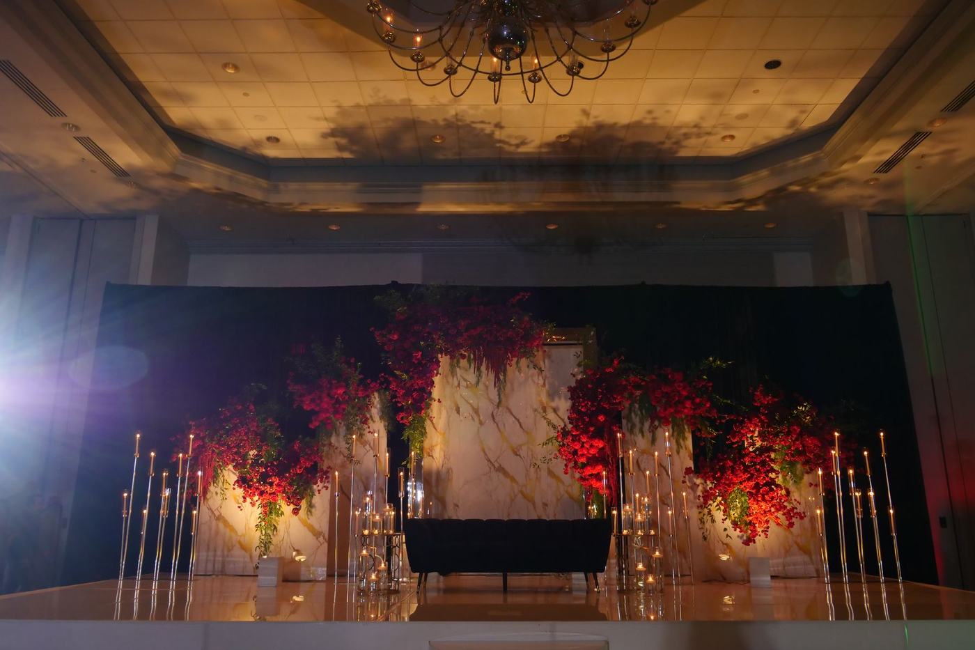 Reception stage dressed with red florals and candelabras