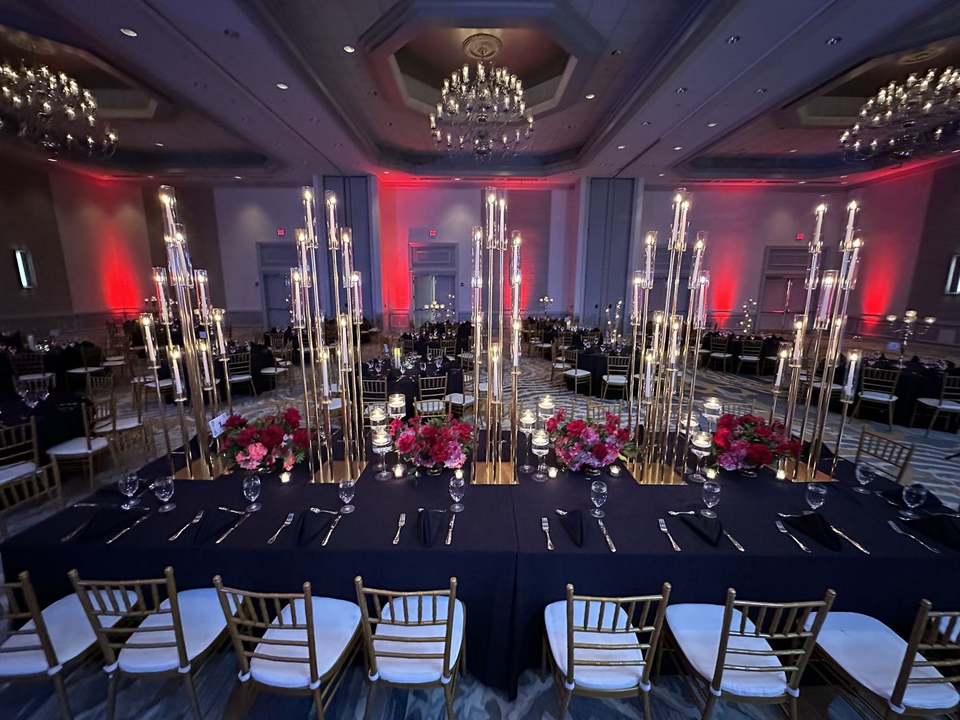 Reception tables with tall candelabras beneath red uplighting