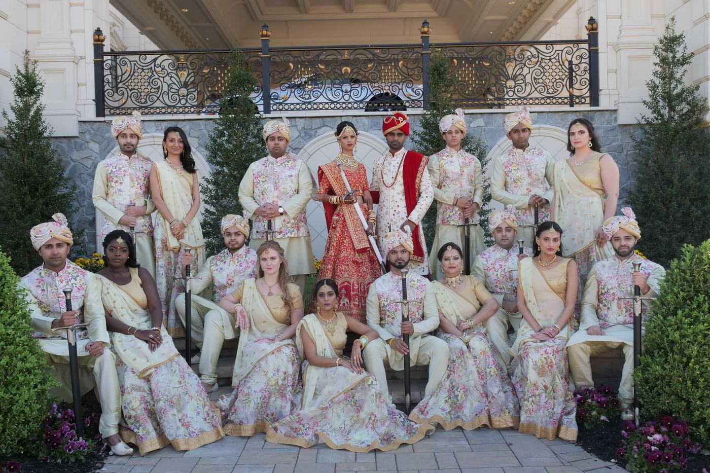The whole wedding party in ivory and red on the estate steps