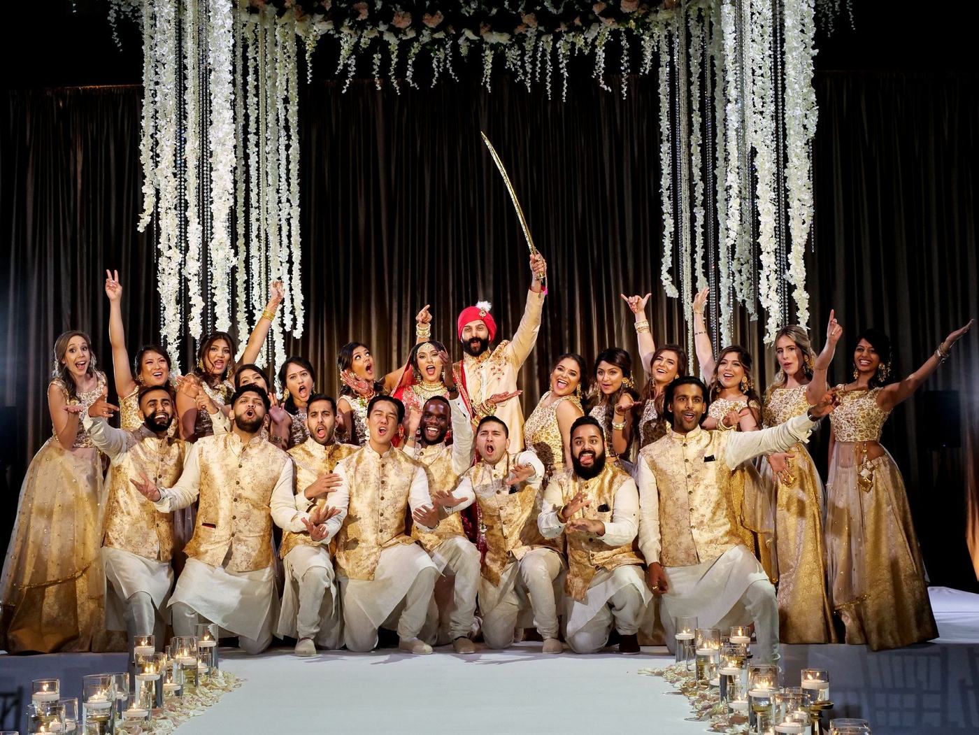The whole wedding party in gold and ivory on the reception stage